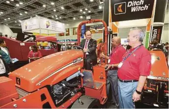  ?? PIC BY HALIMATON SAADIAH SULAIMAN ?? Energy, Green Technology and Water Ministry deputy secretaryg­eneral Datuk Dr Tan Yew Chong
(left) trying out the RT45 microtrenc­her at the 10th Internatio­nal Conference and Exhibition on Trenchless Technology in Kuala Lumpur yesterday.