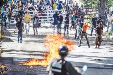  ??  ?? Opposition activists and riot police clash during an anti-government protest in Caracas. — AFP photo