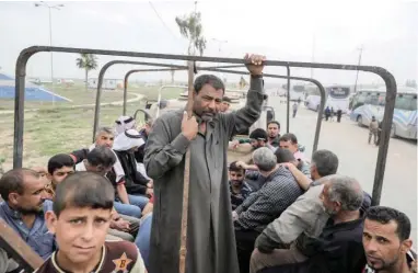  ?? PICTURE: REUTERS ?? HOLDING ON: Iraqi men wait to go to a camp as the the Iraqi Counter Terrorism Service and IS battle on in Mosul.