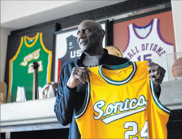  ?? Ellen Schmidt The Associated Press ?? Basketball Hall of Fame member Spencer Haywood shows off his Seattle Supersonic­s No. 24 jersey at his Las Vegas home. The franchise retired Haywood’s number.