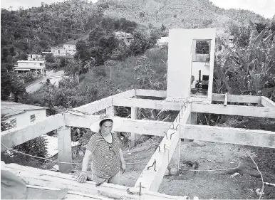  ?? AP ?? Alma Morales Rosario poses for a picture between the beams of her home that is being rebuilt after it was destroyed by Hurricane Maria one year ago in the San Lorenzo neighborho­od of Morovis, Puerto Rico.