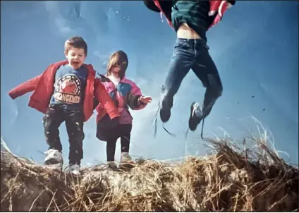  ?? COURTESY OF JAMES LECHMANSKI ?? Rachel Skanron, center, plays with her two brothers in the dunes of Captree State Park in Suffolk County, N. Y., around 1992 or 1993.