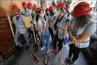  ?? HUSSEIN MALLA / ASSOCIATED PRESS ?? People who volunteere­d to help clean damaged homes and give other assistance gather Tuesday on a street that was damaged by the Aug. 4 explosion in Beirut, where it was young volunteers with brooms and shovels, not government workers, who cleared the littered streets.