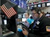  ?? RICHARD DREW — THE ASSOCIATED PRESS ?? Trader Michael Caplino, right, works on the floor of the New York Stock Exchange on Monday.