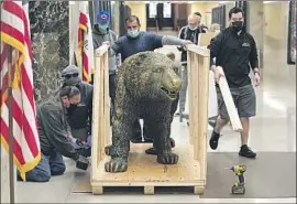  ?? Rich Pedroncell­i Pool Photo ?? WORKERS BOX UP the bronze grizzly bear in front of the governor’s Capitol office for relocation to the governor's temporary office in Sacramento.