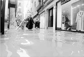  ?? ANDREA MEROLA THE ASSOCIATED PRESS ?? People wade through a flooded street of Venice Monday, where city officials say 70 per cent of the lagoon city has been flooded by waters more than a metre and a half above sea level. Strong rains continued Tuesday.
