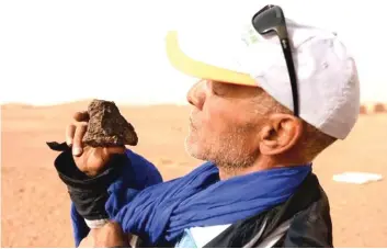  ??  ?? Meteorite hunter Mohamed Bouzgarine examines a rock near the town of M’hamid el-Ghizlane.