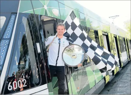  ?? Picture: JULIAN SMITH, EPA ?? ALL ABOARD FOR AN EXCITING DRIVE: Defending Australian Grand Prix champion Nico Rosberg poses for a photo on a tram with the 2014 race winner’s trophy and a chequered flag in Melbourne yesterday ahead of Sunday’s season-opening race.