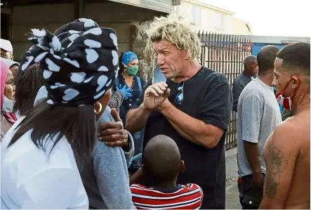  ?? — Photos: AP ?? Steele-smith speaking to residents of the Manenberg neighbourh­ood in Cape town, South africa. Steele-smith recruited gang members to deliver food to homes and soup kitchens during the lockdown.