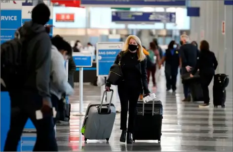  ?? AP FILE PHOTO/NAM Y. HUH ?? In this Sunday file photo, a traveler wears a mask as she walks through Terminal 3 at O’Hare Internatio­nal Airport in Chicago.