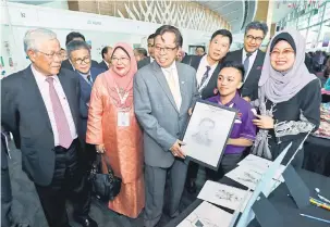  ??  ?? BERKEBOLEH­AN: Abang Johari (tiga kiri) tertarik dengan lukisan wajahnya hasil kerja peserta yang menyertai pameran sempena ICSE di BCCK semalam. Turut kelihatan Manyin (kiri) dan Yasmin (dua kiri).