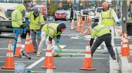  ?? JERRY JACKSON/BALTIMORE SUN ?? A crew from Priceless Industries applies epoxy paint to a bike lane along Central Avenue in Baltimore in November 2022.