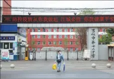  ?? HU HAIFENG / FOR CHINA DAILY ?? A resident of the city of Jilin passes by Jilin No 12 Middle School on Saturday. The school has been temporaril­y closed due to the recent COVID-19 cluster of cases in the city.