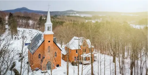  ??  ?? Das Anwesen liegt idyllisch von Bäumen umgeben an einem kleinen Fluss in der Provinz Quebec. Das Kirchenkre­uz ist weithin sichtbar.