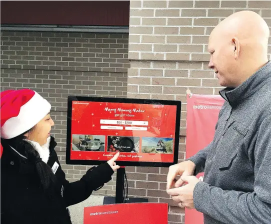  ?? FRANCIS GEORGIAN/ PNG ?? Port Coquitam Mayor Greg Moore, right, tries out Metro Vancouver’s new Merry Memory Maker app at Hyde Creek Recreation Centre in Port Coquitlam. The app makes gift suggestion­s that create less packaging going to the landfill.