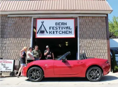  ?? PETER BLEAKNEYFO­R THE TORONTO STAR ?? Volunteers at the Zurich Bean Festival Kitchen in Huron County take a break to check out the new Miata.