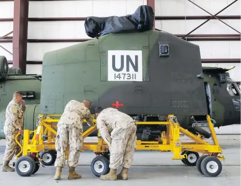  ?? LUKE HENDRY/POSTMEDIA NEWS ?? Canadian Forces technician­s examine a Chinook helicopter at CFB Trenton in Ontario in July, ahead of its deployment as part of Canada’s UN-backed mission in Mali. Canada’s foreign aid commitment has been questioned by the Organizati­on for Economic Co-operation and Developmen­t.