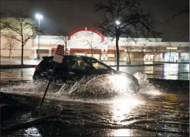  ?? ?? A vehicle drives through a flooded parking lot Wednesday during severe weather in St. Paul, Minn. (AP/Star Tribune/Renee Jones Schneider)*