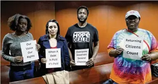  ?? PHOTOS BY BOB ANDRES / BANDRES@AJC.COM ?? Some members of the gallery stand silently with signs after Wednesday’s vote that came after a brief discussion by the Georgia Senate study committee on felon voting rights. The committee voted to maintain the status quo.