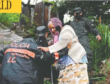  ?? ORLANDO SIERRA / AFP VIA GETTY IMAGES ?? Police officers help an elderly woman in Tegucigalp­a, Honduras, as Hurricane Iota moved toward the country Tuesday.