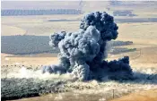  ??  ?? An army soldier deals with a crowd outside a food processing centre in Qayyara, south of Mosul and, left, smoke rises from an Isil position near the town of Naweran