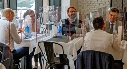  ??  ?? Customers sit behind screens to maintain relaxed social distancing rules in a cafe in Milan yesterday