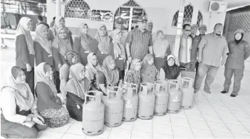  ??  ?? Nizam (standing middle) with the fire victims after handing cash and cooking gas cylinders yesterday.