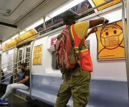  ?? Ap ?? WEAR IT WARNING: A subway worker replaces posters in a car in Brooklyn reminding riders to wear face masks.