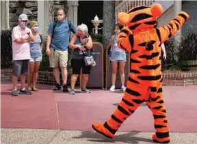  ?? JOE BURBANK/ORLANDO SENTINEL PHOTOS ?? Tigger entertains guests wearing masks as required to attend the official re opening day of the Magic Kingdom at Walt Disney World Saturday.