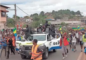  ?? BETINESS MACKOSSO/AP Director of research at the Africa Center for Strategic Studies ?? Supporters of Gabon’s coup cheer police officers Wednesday in the capital, Libreville. The streets there have been jubilant with people celebratin­g alongside the army.