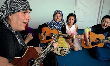  ?? PHOTO: GETTY IMAGES ?? Rock guitarist Lanny Cordola, 56, with children at the Miraculous Love Kids music school, in a room above a supermarke­t in Kabul.