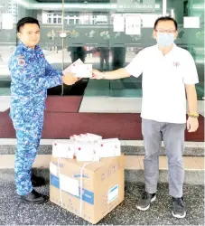  ??  ?? Chan (right) handing over 10 thermomete­rs and 2,000 face masks which were donated by SMEs to Kota Kinabalu Disaster Operations Center.