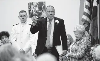  ??  ?? Michael Cokinos, son of Texas Liberator Mike Cokinos, holds up a photo of Holocaust victims his father carried with him. The elder Cokinos “said there were dead bodies piled up in closets.”