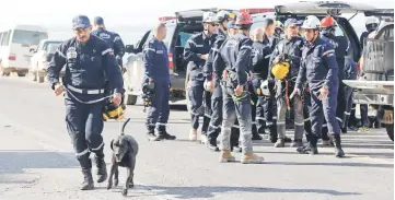  ?? — Reuters photo ?? A search and rescue dog and its handler walk next to civil defence personnel.