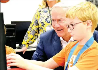  ?? TIMES photograph by Annette Beard ?? Governor Asa Hutchinson watched as Chris Johnson and Colby Radtke (not shown) exhibited the computer game they created. The governor asked Johnson, eighth grade, about the medal he was wearing which was for scoring 23 on the ACT Aspire test as a seventh grader. “Wow — 23 in the seventh grade! Great job,” Gov. Hutchinson said, congratula­ting him. Johnson is the son of Stephanie Schmidt and Caleb Johnson.