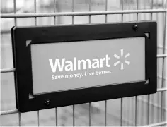  ??  ?? This file photo shows the Walmart logo displayed on a shopping cart at a Walmart store in Chicago, Illinois. Sagging internatio­nal sales held down total revenues and hit profits for retail giant Wal-Mart Stores in the third quarter, the company...