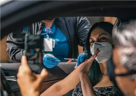  ?? Mark Mulligan / Staff photograph­er ?? Karla De Leon waves for a picture by Pablo Melgar as she receives her COVID-19 vaccine Saturday at the Spring Branch Community Health Center. De Leon and Melgar traveled from Guatemala to get the one-dose Johnson & Johnson shot.