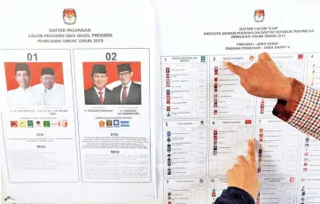  ?? — Reuters photo ?? People point at voting informatio­n at a polling station during elections in Bogor, West Java, Indonesia.