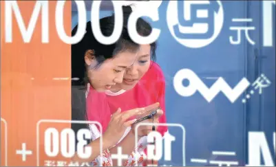  ?? AN XIN / FOR CHINA DAILY ?? Two women surf the web on a mobile phone at an outlet of China Unicom in Nanjing, capital of Jiangsu province.