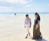  ?? Photo by ?? Tourism Secretary Berna RomuloPuya­t and Karen Davila walk barefoot on the beach. JOANNE RAE RAMIREZ