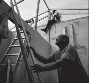  ?? The Associated Press ?? HELPING WORKERS: Pedro Deschamps helps workers hired by FEMA to carry out the installati­on of a temporary awning roof at his house, which suffered damage during Hurricane Maria, on Nov. 15 in San Juan, Puerto Rico. The Department of Homeland Security’s...