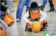  ??  ?? Shawn Ferrell, 3, of Orlando, plays a game of pumpkin bowling during Tuesday night’s Harvest Carnival at the Payne County Fairground­s.