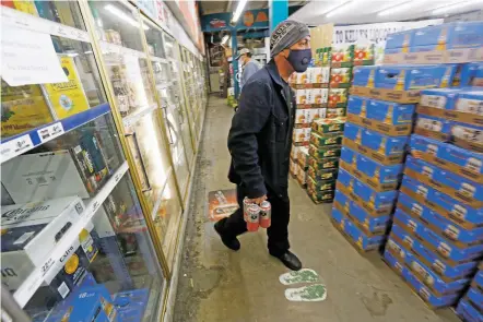  ?? LUIS SÁNCHEZ SATURNO/THE NEW MEXICAN ?? Daniel Smith of Santa Fe gets a six-pack of beer Thursday at Kelly’s Liquor Barn on Cerrillos Road. A sweeping liquor law reform bill has generated pushback from business owners who are concerned about higher prices and potentiall­y devalued liquor licenses.