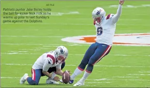  ?? AP FILE ?? Patriots punter Jake Bailey holds the ball for kicker Nick Folk as he warms up prior to last Sunday’s game against the Dolphins.