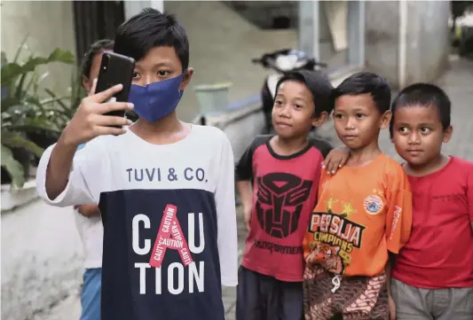  ?? TATAN SYUFLANA AP ?? In September, fifth-grader Qayran Ruby Al Maghribi, left, tested a mobile phone sent to him by Ghina Ghaliya, a journalist who is helping to provide mobile phones for students who lack internet access to study online.