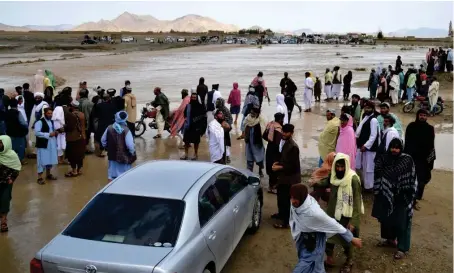  ?? AFP ?? Afghans wait to cross a flooded area in the Spin Boldak district of Kandahar province on Saturday after a flash flood following a heavy rainfall.