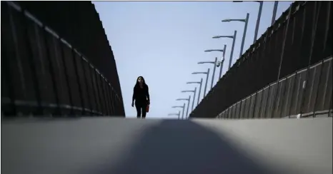  ?? AP PHOTO/GREGORY BULL ?? A woman walks towards the border on a pedestrian bridge over constructi­on on a new curve along California’s Interstate 5, as it approaches the border with Tijuana, Mexico, in San Diego, Tuesday.