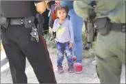  ?? John Moore / Getty Images ?? A Mission Police Department officer, left, and a U.S. Border Patrol agent watch over a group of Central American asylum seekers before taking them into custody on Tuesday near McAllen, Texas.