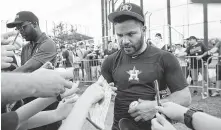  ??  ?? Even after practice, Astros second baseman Jose Altuve still has work to do as he accommodat­es fans seeking an autograph.