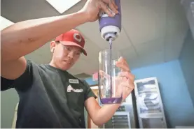  ?? GRETA CROSS/SPRINGFIEL­D NEWS-LEADER ?? Marco Bautista fills a cup full of ube-flavored sauce at Filipino Market Boba & Market on Aug. 11.